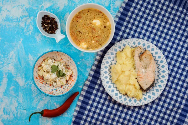 Obědová souprava z lososového steaku s bramborovou kaší, mrkvovou polévkou, salátem. — Stock fotografie