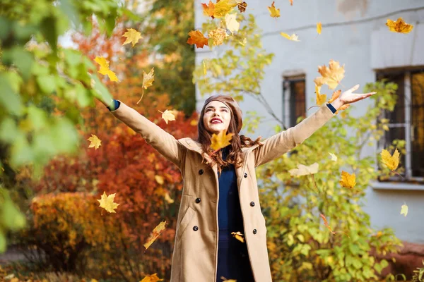 Stilvolle Frau wirft Herbstblätter ab und hat Spaß im Freien in der Herbstsaison. — Stockfoto