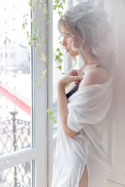 一杯のコーヒーと白いシャツで朝の窓に近い美しいかわいい女の子 — ストック写真