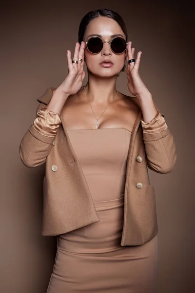 Vacker affärskvinna i en business klänning och glasögon på brun bakgrund i studion — Stockfoto