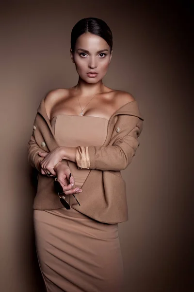 ビジネス ドレスとスタジオで茶色の背景にガラスの美しい女性 — ストック写真