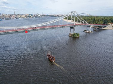 Hava aracı görüntüsü. Kiev 'deki Dinyeper Nehri boyunca bir korsan motorlu tekne köprünün altından geçiyor..