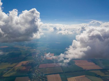 Yaz mevsiminde tarımsal tarlalar üzerinde bulutlarda yüksek uçuş.