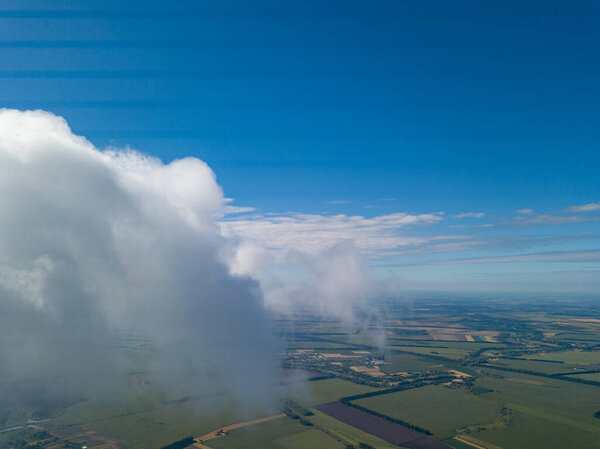 High flight in the clouds over agricultural fields.