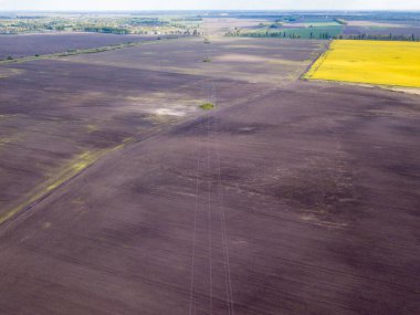 Hava aracı görüntüsü. Tarlaların arasında bir elektrik hattı direği. Güneşli bahar günü.