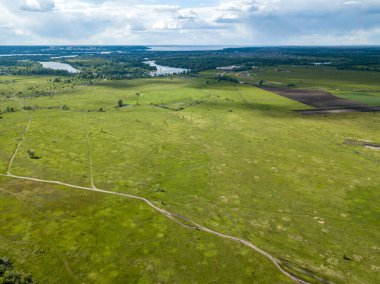 Hava aracı görüntüsü. Yeşil bir çayırda kirli bir yol.