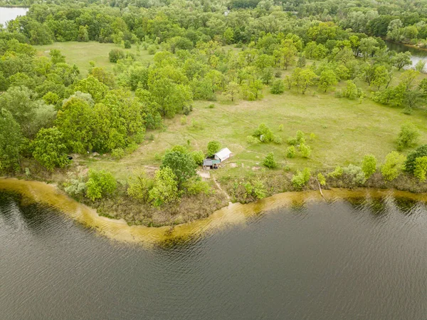 Aerial drone view. Lonely building in the middle of the forest on the river bank.