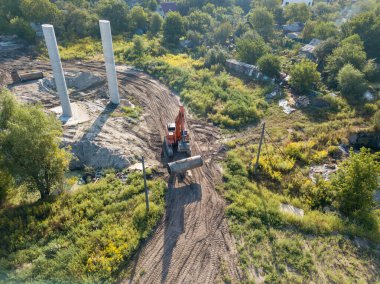 Hava aracı görüntüsü. Köprü inşaatında turuncu kazıcı.