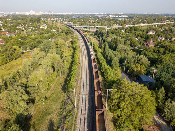 Aerial drone view. Freight train travels by rail in the city.