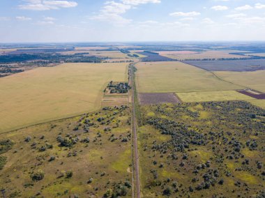 Hava aracı görüntüsü. Nadir çalılarla dolu bir çayırdan geçen demiryolu..