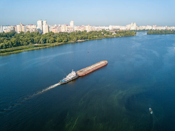 The barge floats on the Dnieper river in Kiev. Sunny weather. Aerial drone.