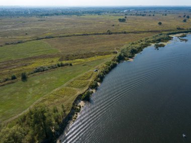 Hava aracı görüntüsü. Yeşil çayırlar arasında geniş bir nehrin kıvrımı. Güneşli yaz günü.