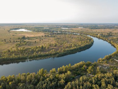 Hava aracı görüntüsü. Yeşil çayırlar arasında geniş bir nehrin kıvrımı. Güneşli yaz günü.