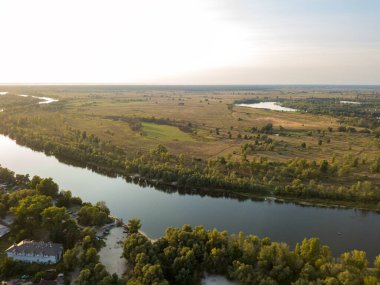 Hava aracı görüntüsü. Yeşil çayırlar arasında geniş bir nehrin kıvrımı. Güneşli yaz günü.