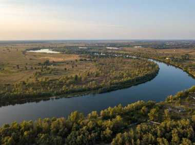 Hava aracı görüntüsü. Yeşil çayırlar arasında geniş bir nehrin kıvrımı. Güneşli yaz günü.