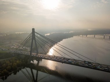 Hava aracı görüntüsü. Güneşli bir sabahta Kiev 'in kuzey köprüsü. Sonbahar sisi havada, arabalar köprüden geçiyor..