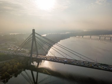 Hava aracı görüntüsü. Güneşli bir sabahta Kiev 'in kuzey köprüsü. Sonbahar sisi havada, arabalar köprüden geçiyor..