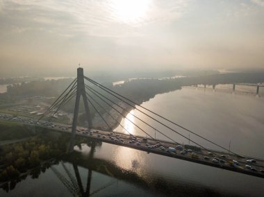 Hava aracı görüntüsü. Güneşli bir sabahta Kiev 'in kuzey köprüsü. Sonbahar sisi havada, arabalar köprüden geçiyor..