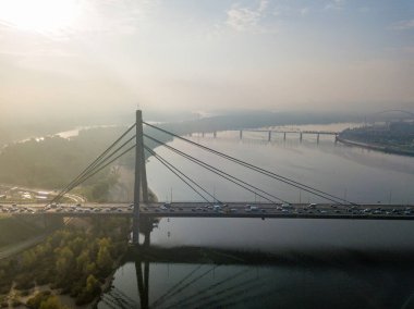 Hava aracı görüntüsü. Güneşli bir sabahta Kiev 'in kuzey köprüsü. Sonbahar sisi havada, arabalar köprüden geçiyor..