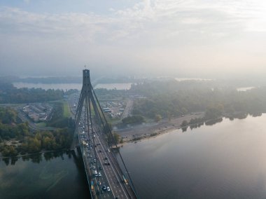 Hava aracı görüntüsü. Güneşli bir sabahta Kiev 'in kuzey köprüsü. Sonbahar sisi havada, arabalar köprüden geçiyor..