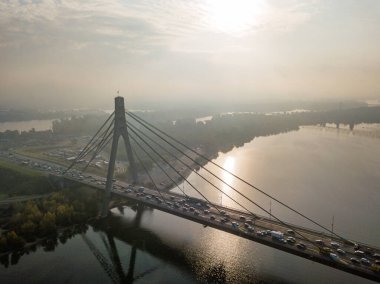 Hava aracı görüntüsü. Güneşli bir sabahta Kiev 'in kuzey köprüsü. Sonbahar sisi havada, arabalar köprüden geçiyor..