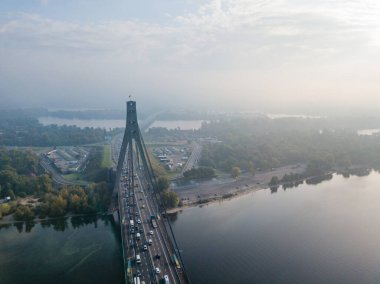 Hava aracı görüntüsü. Güneşli bir sabahta Kiev 'in kuzey köprüsü. Sonbahar sisi havada, arabalar köprüden geçiyor..