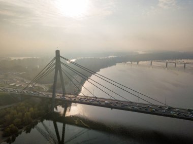 Hava aracı görüntüsü. Güneşli bir sabahta Kiev 'in kuzey köprüsü. Sonbahar sisi havada, arabalar köprüden geçiyor..