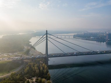 Hava aracı görüntüsü. Güneşli bir sabahta Kiev 'in kuzey köprüsü. Sonbahar sisi havada, arabalar köprüden geçiyor..