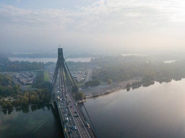 Hava aracı görüntüsü. Güneşli bir sabahta Kiev 'in kuzey köprüsü. Sonbahar sisi havada, arabalar köprüden geçiyor..
