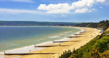 Altın kumsalları ve mavi-yeşil denizler Bournemouth arasındaki Poole Dorset Sahili boyunca güneş ışığı yanar