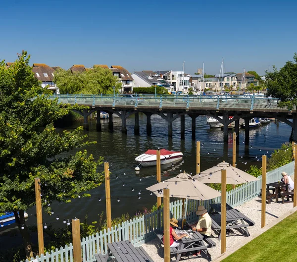 Bir demir köprü Tuckton köprü Dorset İngiltere River Avon nehri kıyısında bir yemek keyfi kişi ile bir sıcak yaz gününde yayılan