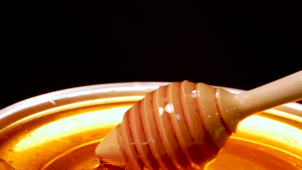 木制勺子在黑色背景上从透明的碗中采集蜂蜜 有选择的重点 — 图库视频影像