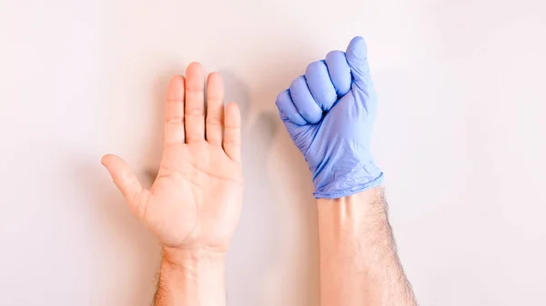 Image 5 of a sequence of images in which a man\'s hands taking off blue disposable gloves medical. Top view. Selective focus