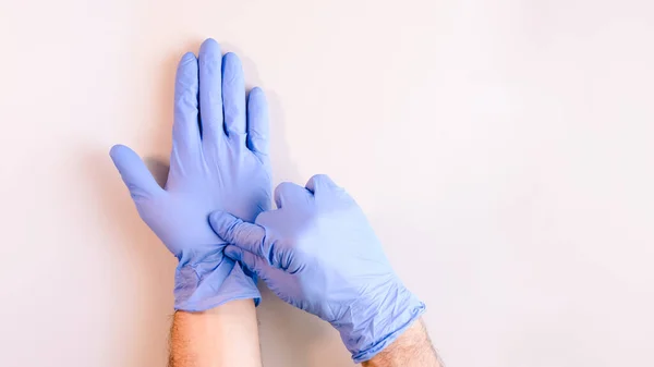 Image 2 of a sequence of images in which a man\'s hands taking off blue disposable gloves medical. Top view. Selective focus