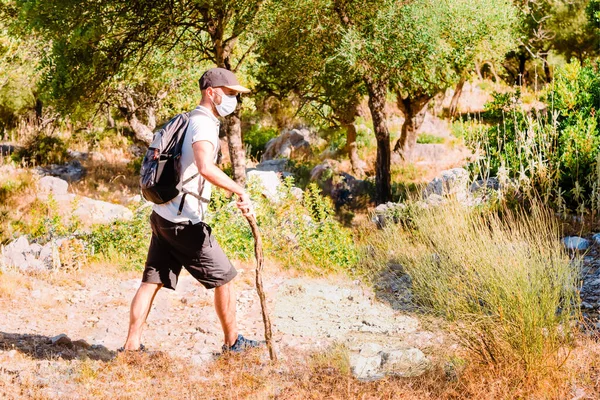 Young man with a medical mask hiking on a road of the ancient Roman Empire. Selective focus