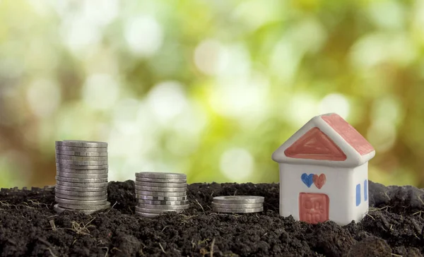 house and coins in soil, saving money to build a house concept