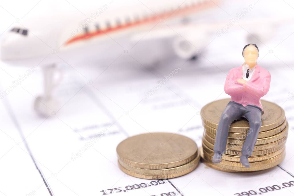 Miniature businessman and stack coins on statement and the airplane behind. saving and loan concept. 