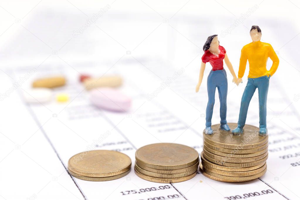Miniature couple people and stack coins on statement and the drug behind. saving concept. 