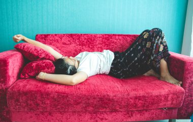 Evdeki kanepede uyuyan genç kadın.