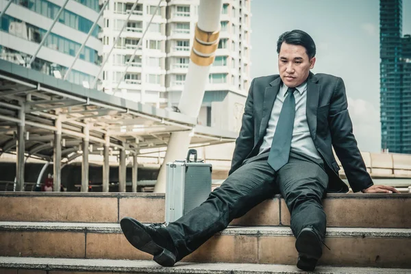 Merdivenlerde oturan genç depresif iş adamı