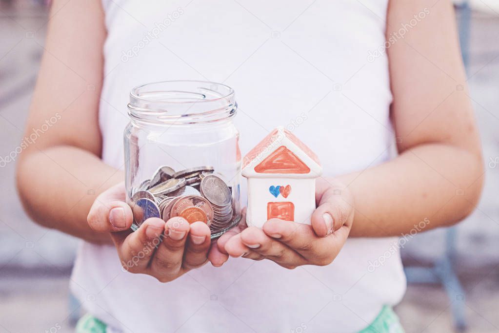 Small kid hands holding house and coins