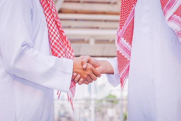 Arabic businessman giving an handshake to his business partner, on construction site