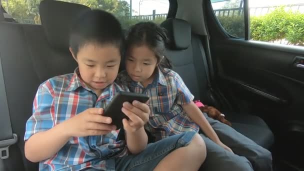 Anak Kecil Yang Bahagia Mengenakan Sabuk Pengaman Memegang Smartphone Mobil — Stok Video