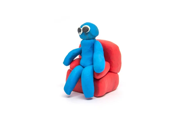 Play dough man sitting on red sofa on white background — Stock Photo, Image