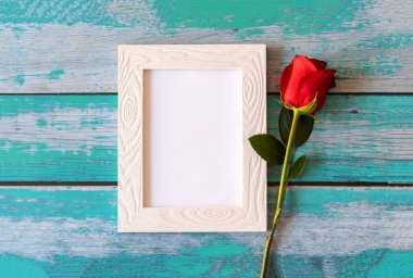 Boş fotoğraf çerçevesi ve ahşap masanın üzerinde kırmızı güller.