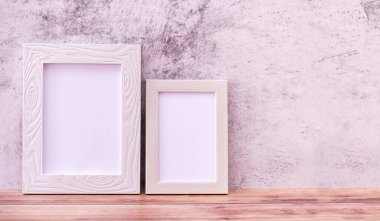 Arka planda iki resim çerçevesi ve ahşap masa. Poster ürün tasarımı biçiminde