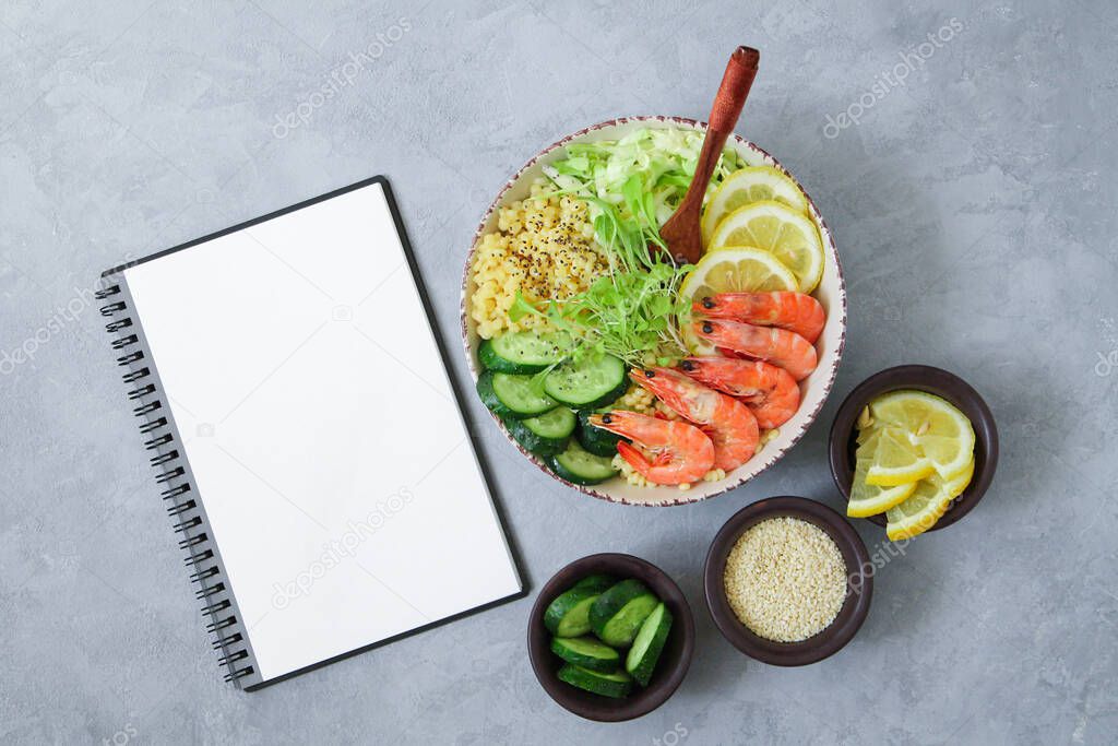 Balanced and healthy Buddha Bowl and blank notepad top view on light gray stone table. Ingredients for trend salad