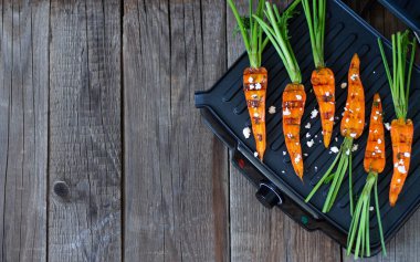 Barbekü havuçları ızgaranın üstünde tahta masa üzerinde fotokopi alanı ile birlikte. Yaz temizliği ızgara sebze konsepti