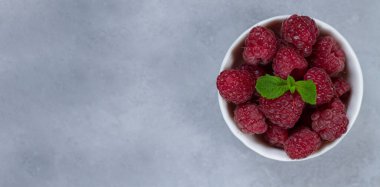 Taze olgun ahududu beyaz kâse içinde taş masanın üstünde. Metin için boşluk