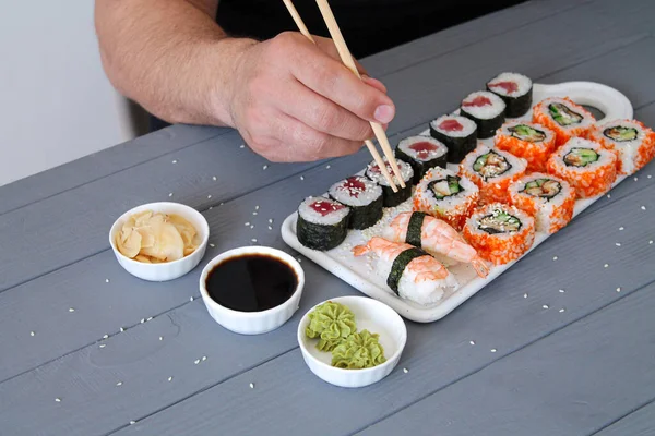 Mann Hält Essstäbchen Der Hand Und Isst Köstliches Sushi Einem — Stockfoto